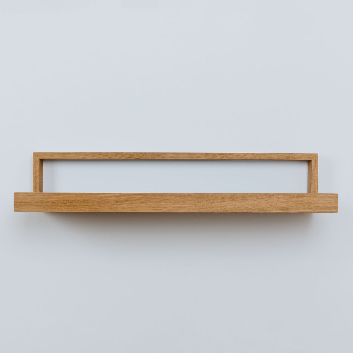 Schlankes Wandregal »buck« von das kleine b in Größe 2, aus geöltem Eichenholz mit anthrazitfarbenem Möbellinoleum. Rechteckige, minimalistische Form, klare Linien, sichtbare Holzstruktur, an einer hellen Wand montiert. Modern und vielseitig einsetzbar.