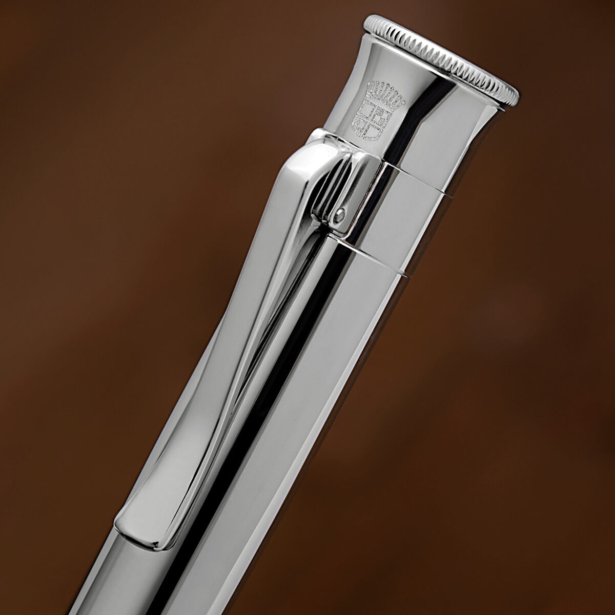 Nahaufnahme eines luxuriösen silbernen Bleistifts mit glänzender Oberfläche und Clip vor einem braunen Hintergrund.