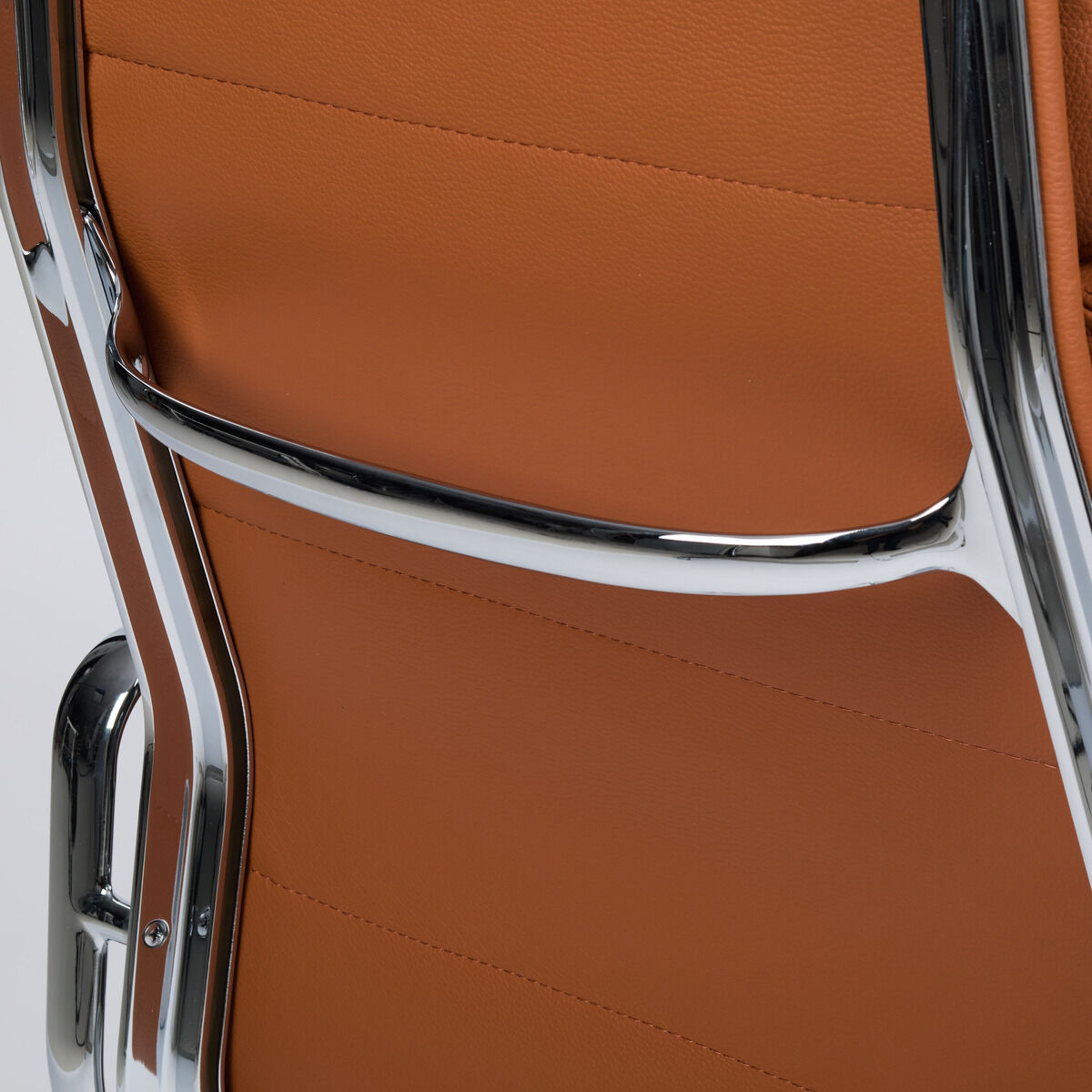 Detailansicht der Rückenlehne des Vitra Soft Pad EA219 Schreibtischstuhls in der ZEIT-Sonderedition: Hochwertiges, cognacfarbenes Leder, umgeben von glänzendem, verchromtem Aluminiumgestell. Feine Ziernähte und elegante Verarbeitung verleihen dem Stuhl modernen Luxus.