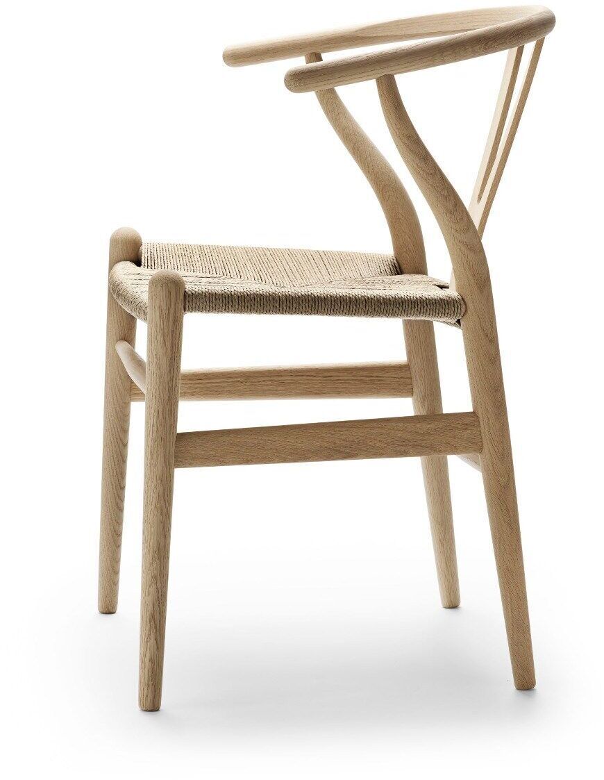 Ein eleganter Stuhl von Carl Hansen & Søn, Modell Wishbone Chair CH24, aus hellem Holz mit geschwungenen Linien und einer geflochtenen Sitzfläche.