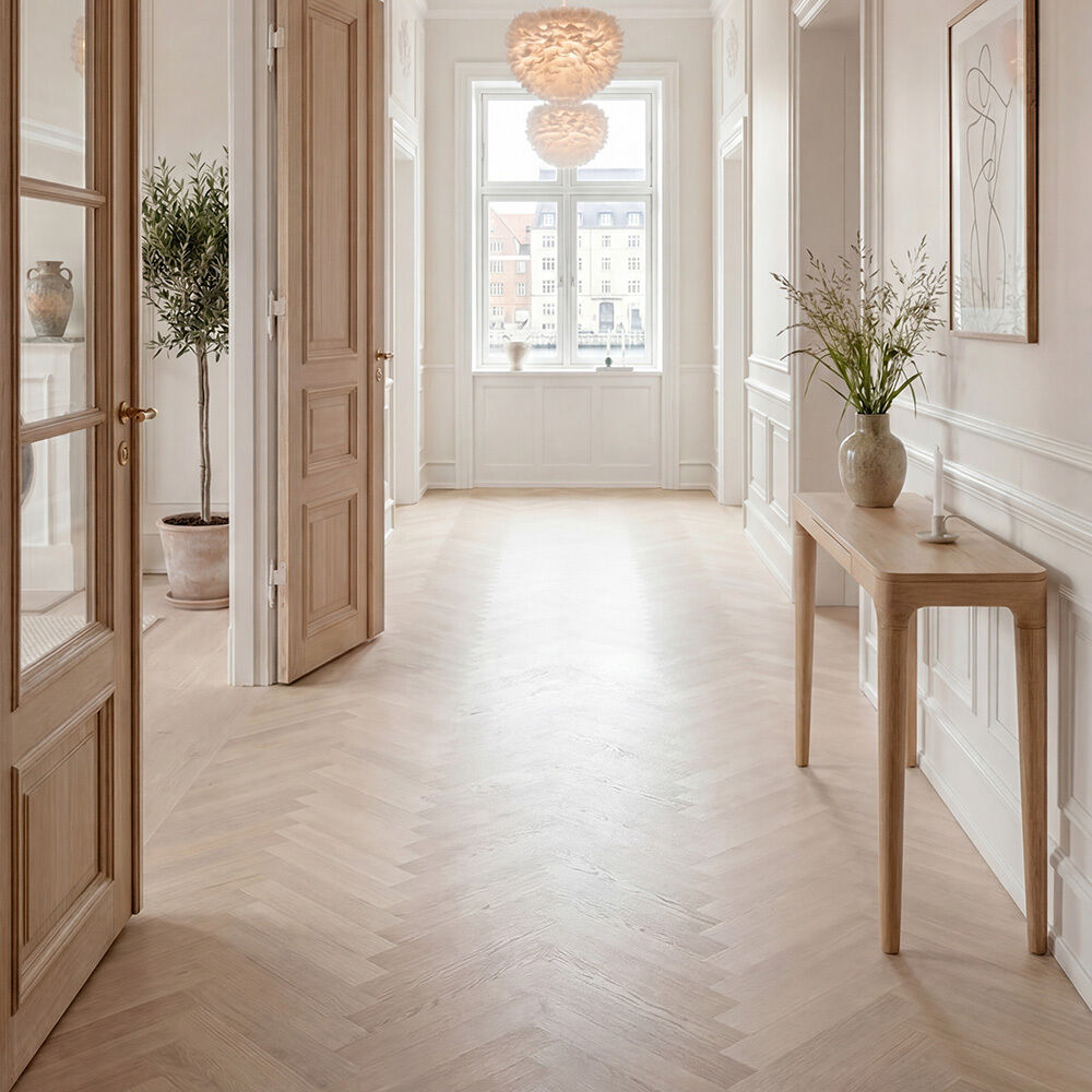 Heller Flur mit skandinavischem Einrichtungsstil, zentral platziert der Konsolentisch »Heart'n'Soul« von Umage aus massiver Eiche. Auf dem Tisch eine Vase mit Blumen, an der Wand ein minimalistisches Bild, bodentiefer Topf mit Olivenbaum, große Fenster, dezente Dekoration.