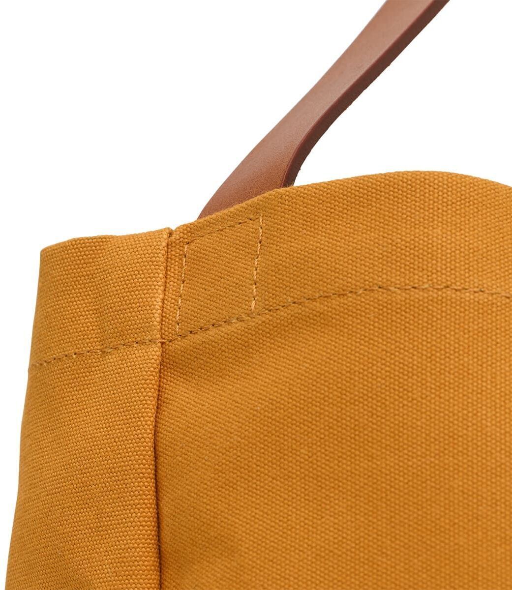 Nahaufnahme einer hochwertigen gelben Stofftasche mit braunem Griff. Die Naht ist sauber und robust verarbeitet.