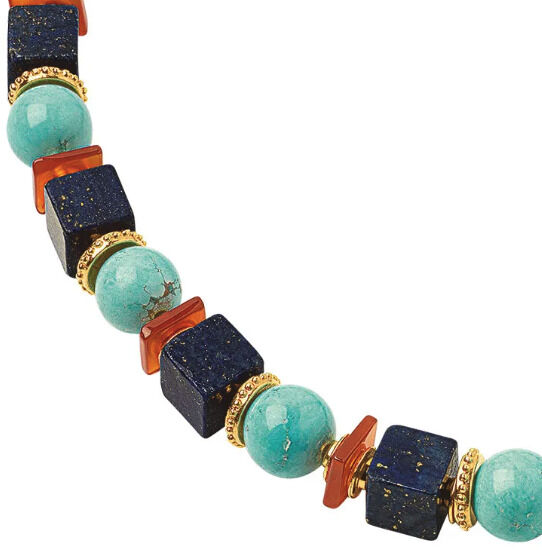 Detail einer kunstvoll gestalteten Halskette von Petra Waszak aus der Kollektion 'Jasmin'. Die Kette zeigt abwechselnd türkisfarbene, runde Perlen und blau-goldene sowie orangefarbene Würfel, verbunden durch goldene Abstandshalter.