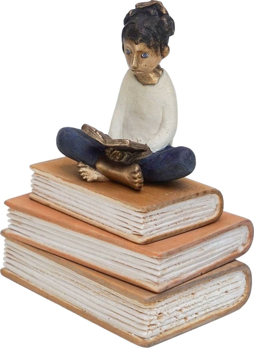 Skulptur einer Figur, die auf gestapelten Büchern sitzt und liest, mit blauer Hose und weißem Oberteil. Die Farben sind vorwiegend braun, blau, weiß und gold.