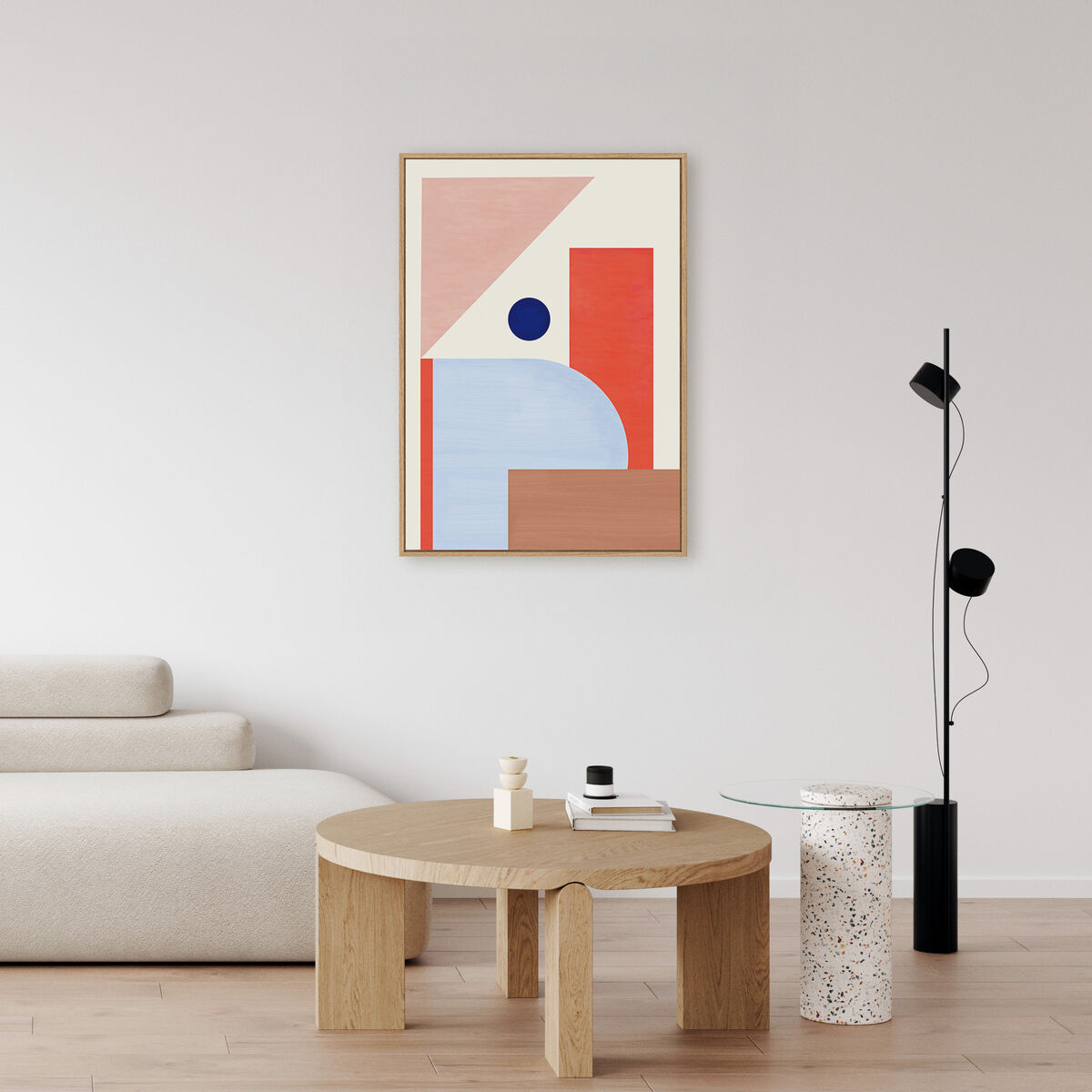 Ein modernes Leinwandbild mit abstrakten, geometrischen Formen in hellen Pastelltönen, darunter Beige, Hellblau und Koralle. Das Kunstwerk hängt in einem minimalistisch eingerichteten Wohnzimmer mit hellem Sofa, rundem Holztisch und stilvollem Lampenständer. Die Szene vermittelt ein zeitgemäßes und ästhetisches Wohnambiente.