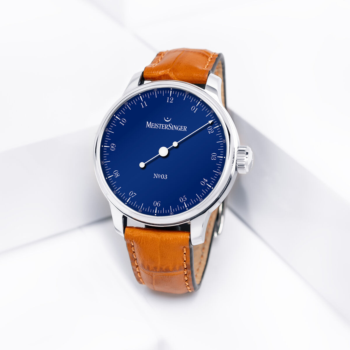 Automatikuhr MeisterSinger ZEIT-Sonderedition »N°03« mit tiefblauem Zifferblatt, silberfarbenem Edelstahlgehäuse und braunem Lederarmband. Das minimalistische Design hebt die feinen weißen Indizes hervor. Das Uhrenmodell liegt elegant auf einer weißen, geometrischen Oberfläche.