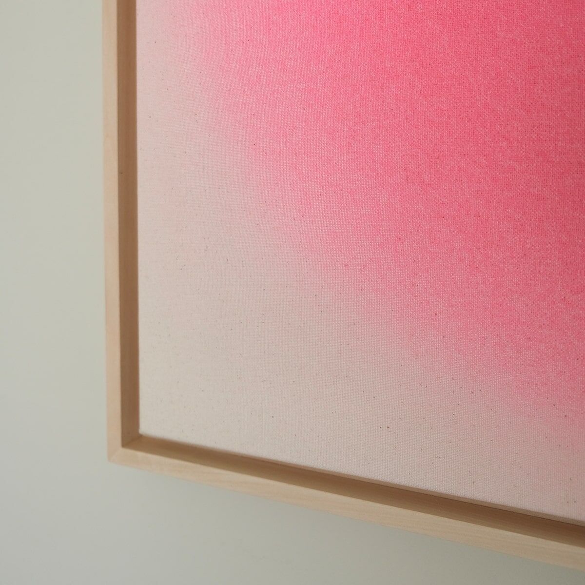 Ein quadratisches Kunstwerk mit den Maßen 59x59 cm zeigt eine Farbverlauf von Weiß zu Pink. Das Bild ist in einem schlichten, hölzernen Rahmen eingefasst und hat eine minimalistische Ästhetik.