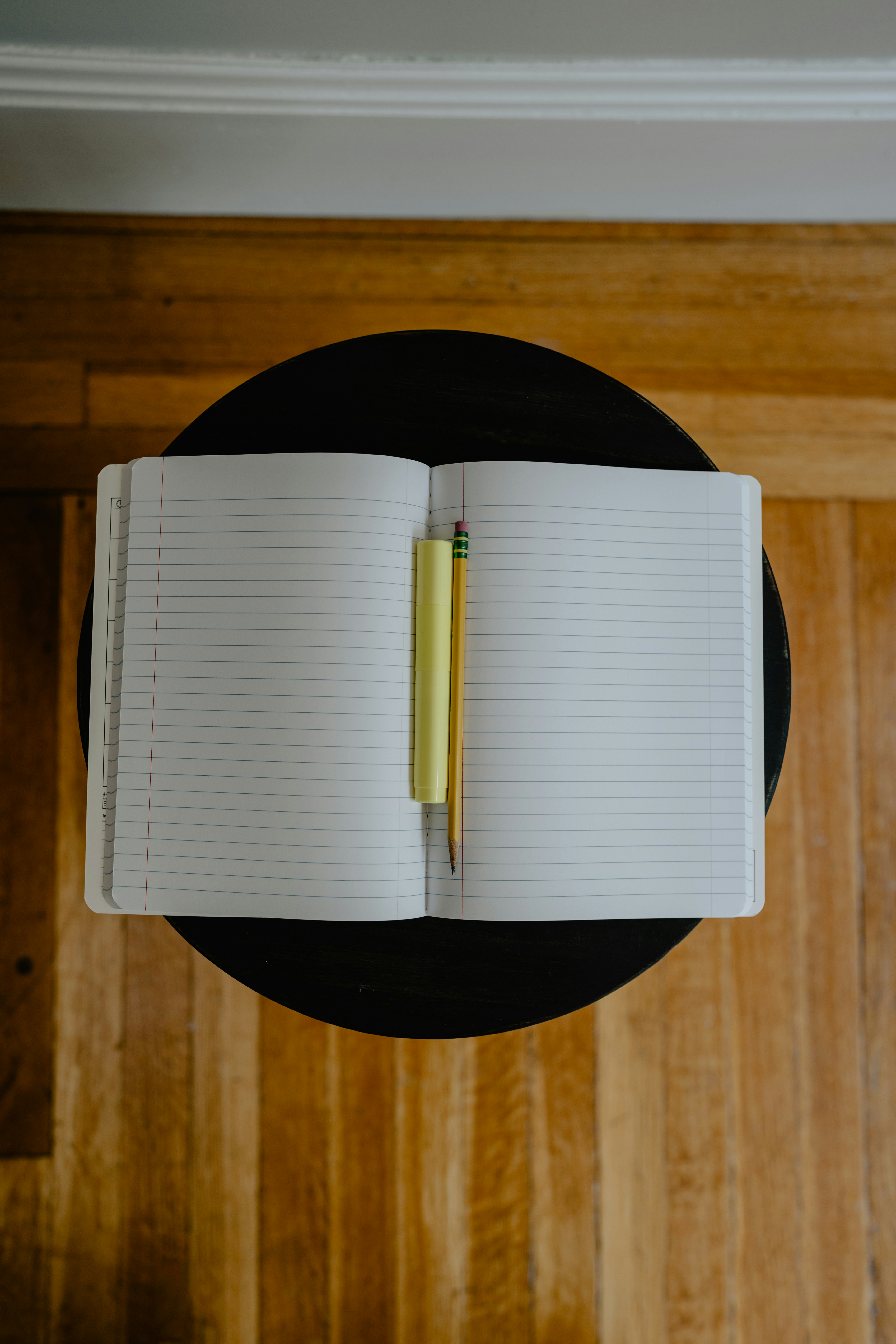 alt="Notizbuch aufgeklappt mit linierten Seiten und zwei Stiften in der Mitte des Buches"