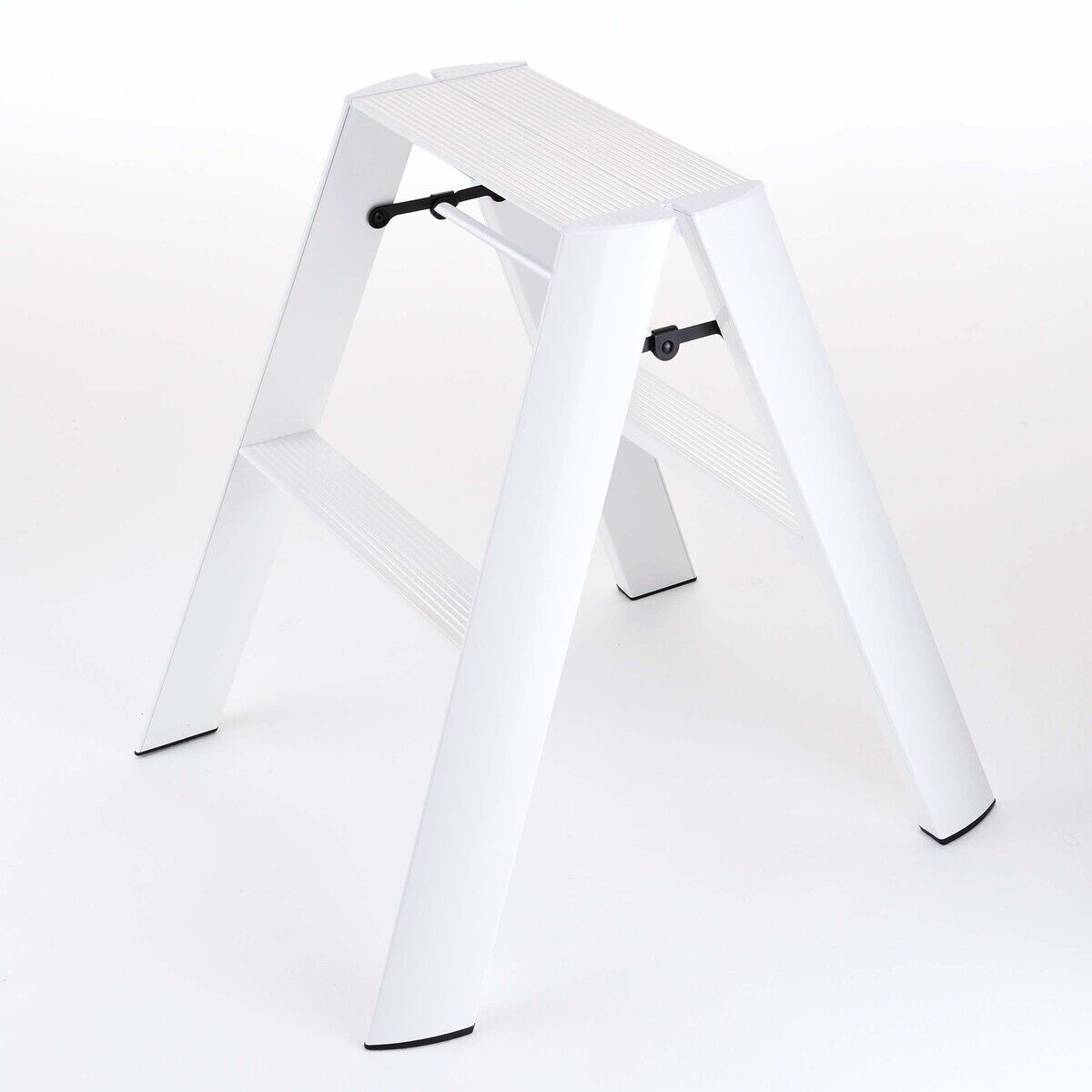 Eine moderne, weiße Trittleiter mit zwei Stufen steht auf einer hellen Oberfläche. Das Design ist minimalistisch und funktional, mit rutschfesten Stufen und schwarzen Standfüßen. Die Leiter eignet sich ideal für den Gebrauch im Haushalt oder bei leichten Montagearbeiten.