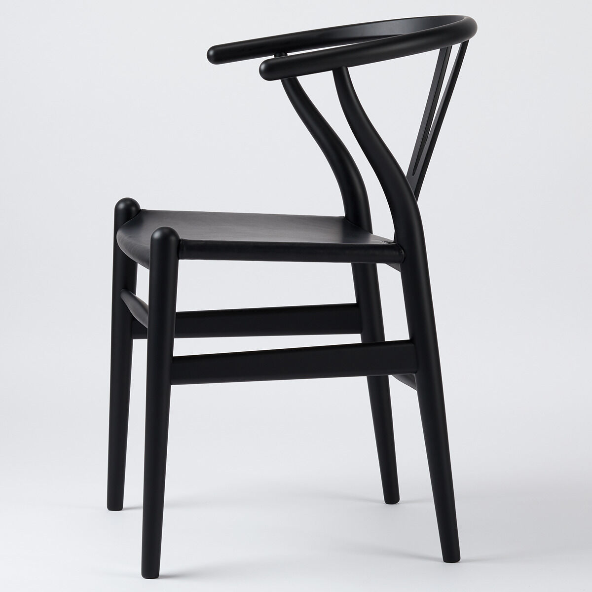 Schwarzer Wishbone Chair aus Buchenholz und Leder mit elegant geschwungenen Armlehnen und minimalistischer Form, stehend auf einem weißen Hintergrund.