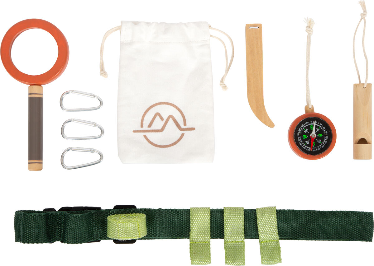 Auf dem Bild sind verschiedene Outdoor-Entdeckungswerkzeuge zu sehen, darunter eine grüne Gürteltasche, eine orangene Lupe, ein Kompass, Karabinerhaken und ein Baumwollsäckchen. Diese Utensilien sind perfekt für Kinder, die gerne in der Natur spielen und Abenteuer erleben.