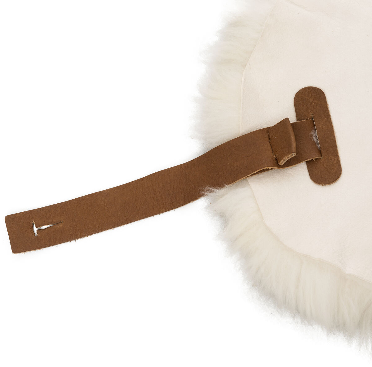 Ein cremeweißes Schafsfell mit einer hellbraunen Lederschlaufe liegt ausgebreitet auf weißem Hintergrund. Das Fell wirkt flauschig und naturbelassen; die Schlaufe aus Leder ist funktional befestigt. Das Produkt eignet sich als dekorativer und wärmender Heimtextilien-Artikel.
