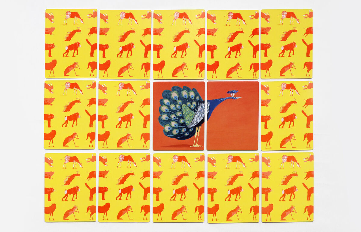 Ein Memory-Spiel mit 16 Karten, auf denen verschiedene Tiere in gelb, orange, blau und grün Farben illustriert sind. Eine der Karten zeigt einen Pfau mit blau-grünem Gefieder.
