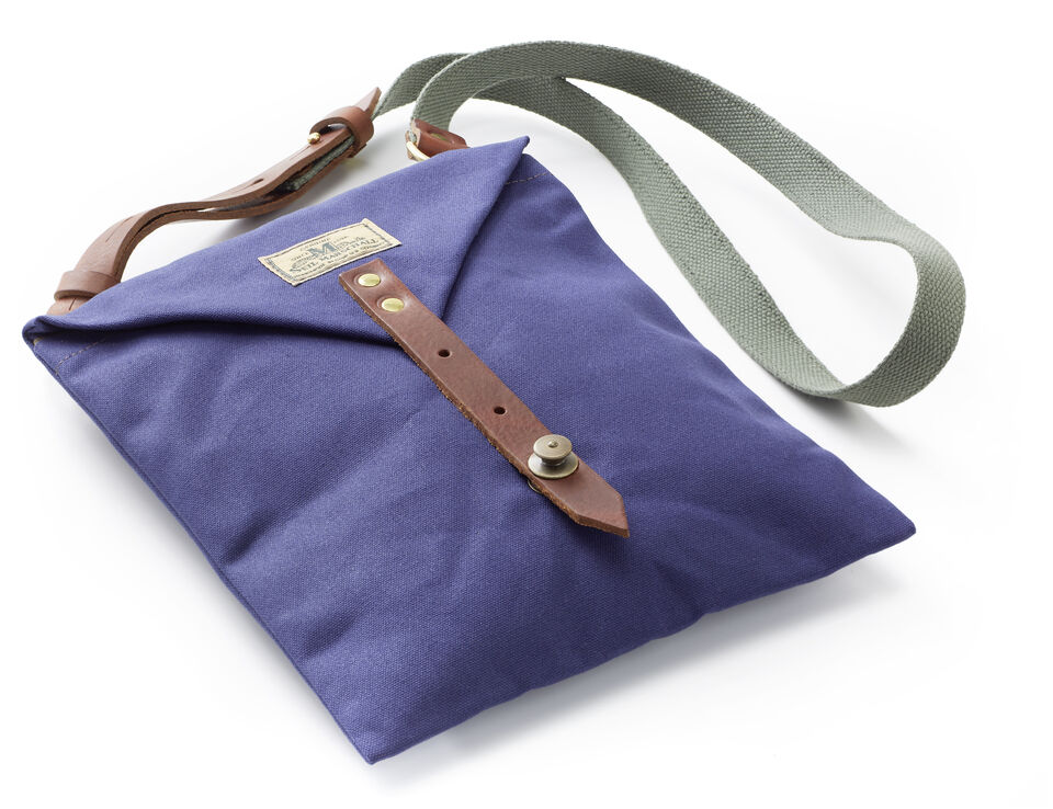 Eine blaue Kartentasche aus Segeltuch mit einem Knopfverschluss aus Leder und einem grauen Schulterriemen. Ideal für Outdoor-Aktivitäten wie Wandern oder Camping.