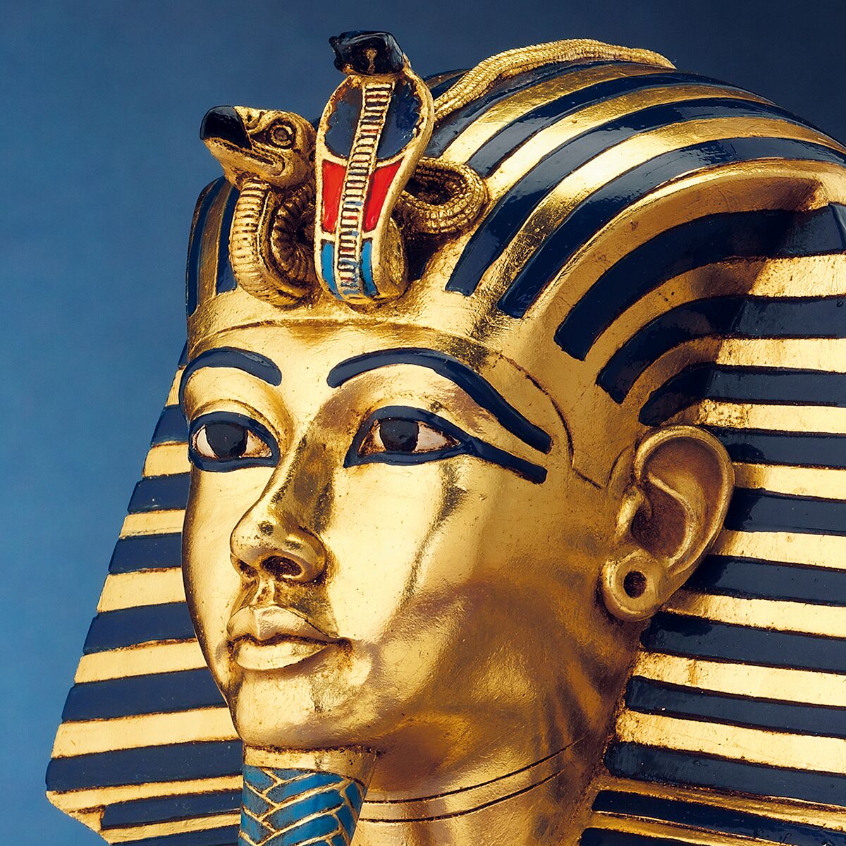 Detailreiche Büste der Goldmaske des Tutanchamun als hochwertige Replik aus polymerem Kunstguss. Die Figur zeigt das ikonische Gesicht mit goldener Oberfläche, blauen und schwarzen Streifen am Kopfschmuck, feinen Detailmalereien und farbigen Schmuckelementen auf weißem Hintergrund.