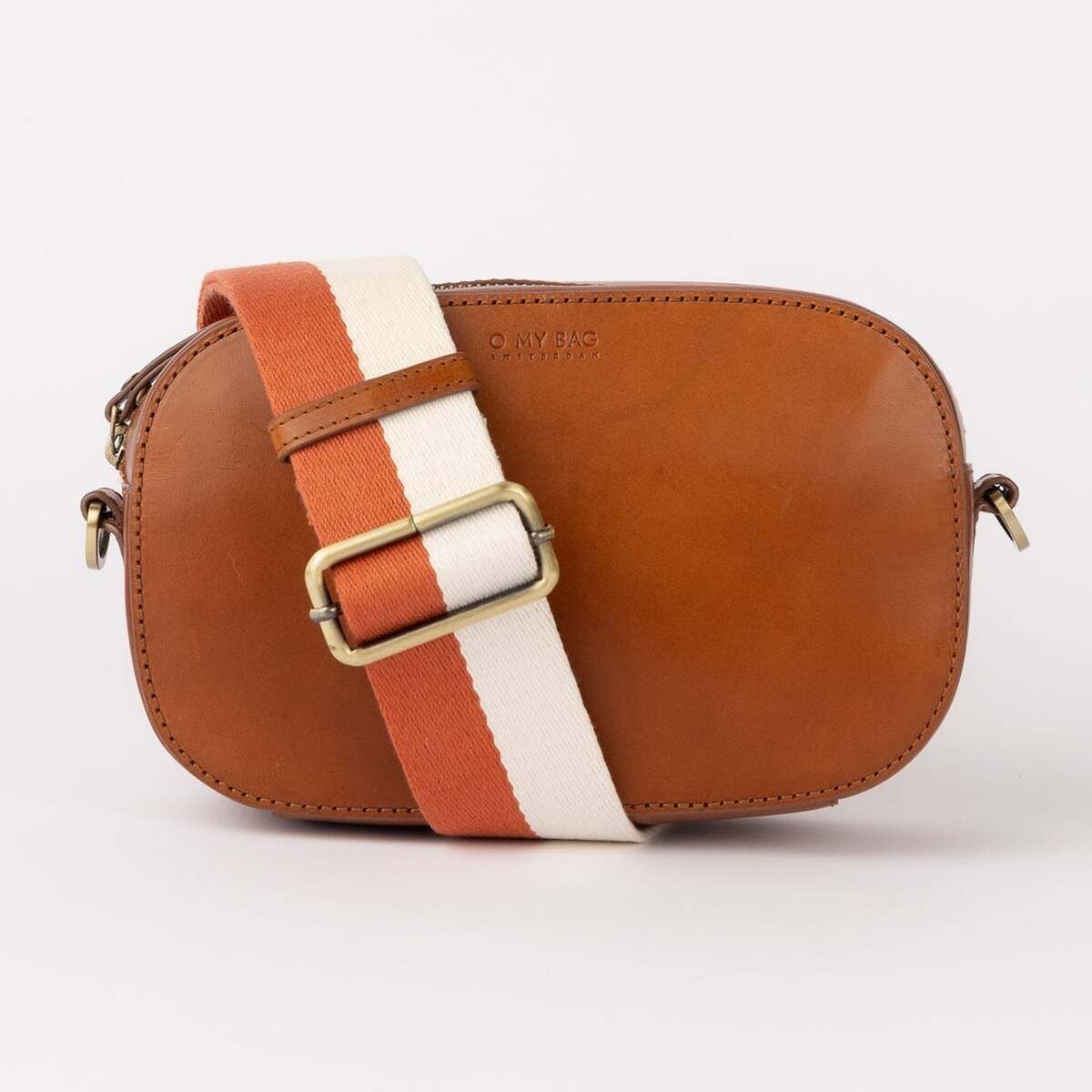Kleine Leder-Umhängetasche 'Maya' mit verstellbarem Gurt in Orange und Weiß, aus Stoff. Das Leder ist cognacfarben. Die Beschläge in antiken Messing. Das Design ist modern und minimalistisch mit goldfarbener Schnalle am Gurt.