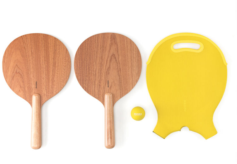 Ein Beachball-Set, bestehend aus zwei braunen Holzschlägern, einem gelben Ball und einem gelben Handfänger, ideal für Sommeraktivitäten und Strandspiele.