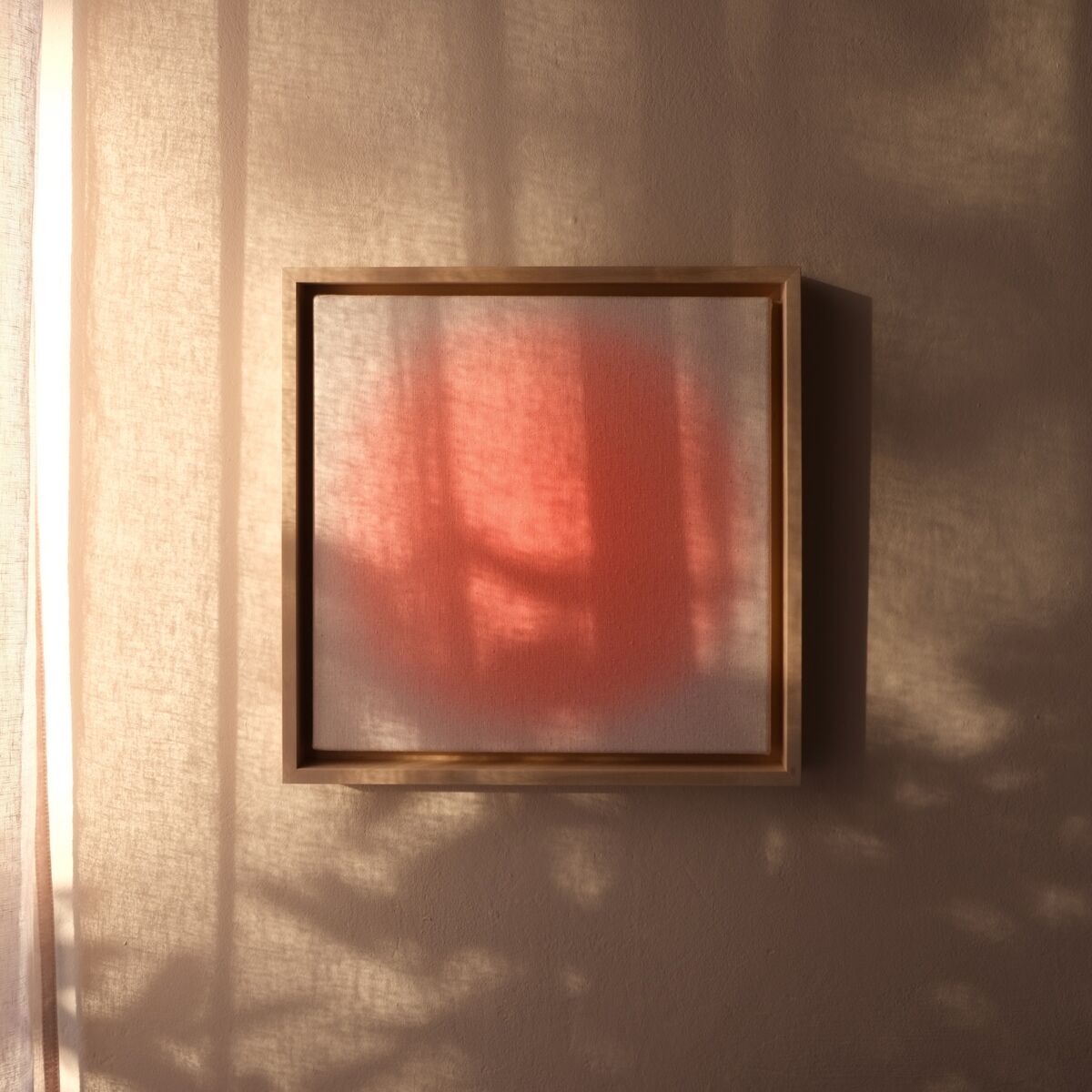 Quadratisches Kunstwerk mit zarten apricot-rosa Tönen, abstrahiertem Farbverlauf und sanften Schatteneffekten, gerahmt und an einer von Sonnenlicht beschienenen Wand hängend.