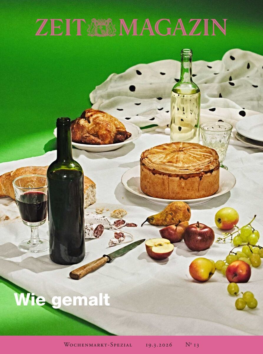 Das Titelbild des ZEIT Magazins Ausgabe 13/26 zeigt einen opulenten, künstlerisch arrangierten gedeckten Tisch auf weißem Tuch mit Brot, Torten, Obst, Trauben, Wein, einem Glas Rotwein und mehreren Flaschen. Im Hintergrund grüner Farbverlauf und Magazinlogo in Pink.