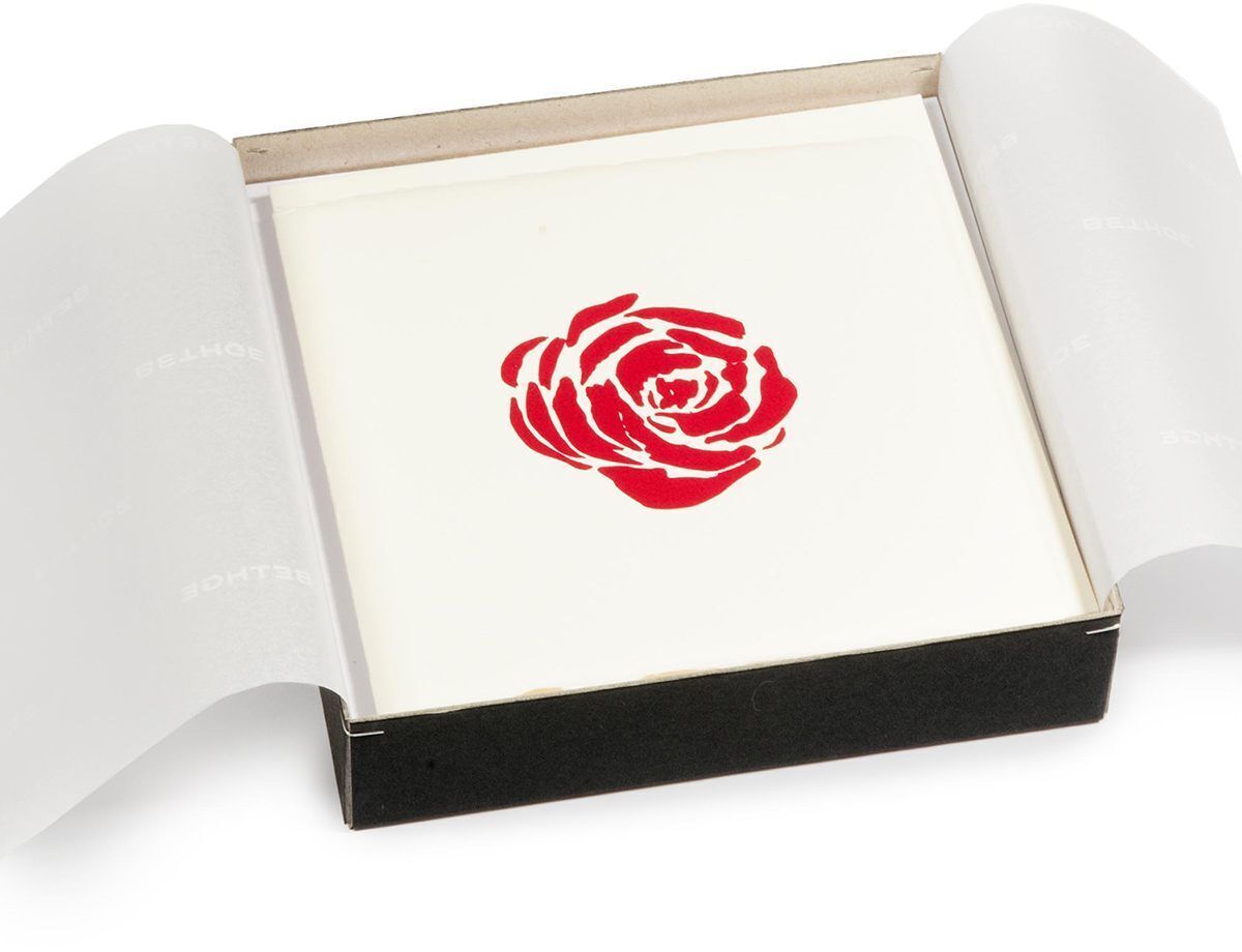 Ein 8-teiliges Grußkarten-Set mit dem Titel »Blumige Grüße«. Das Set enthält Karten mit einem roten Rosenmotiv auf weißem Hintergrund, verpackt in einer schwarzen Schachtel.