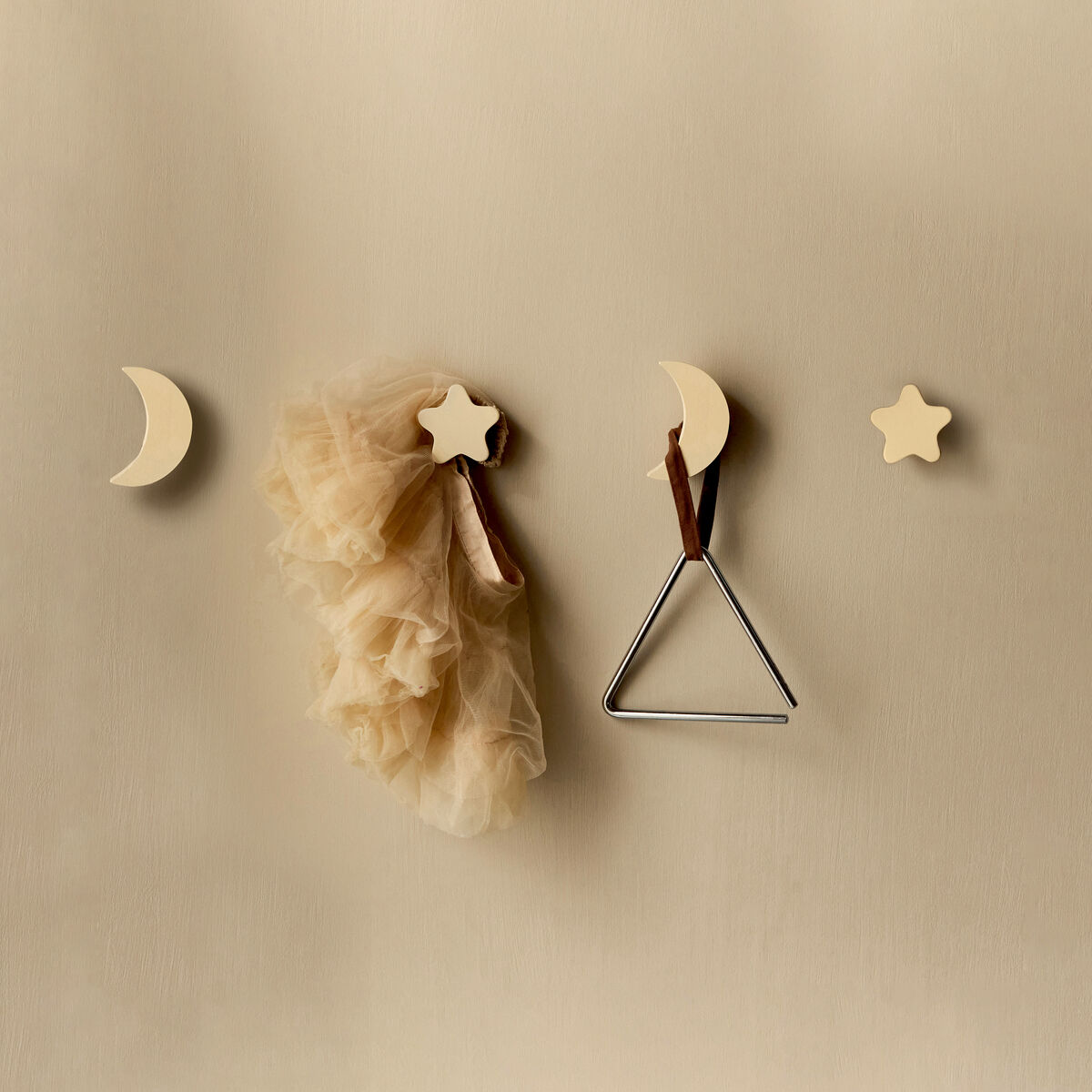 Ein Set von hölzernen Wandhaken in Form von Sternen und Monden in beige und braun. Sie sind an einer einfarbigen Wand befestigt und eignen sich zur Dekoration von Kinderzimmern.