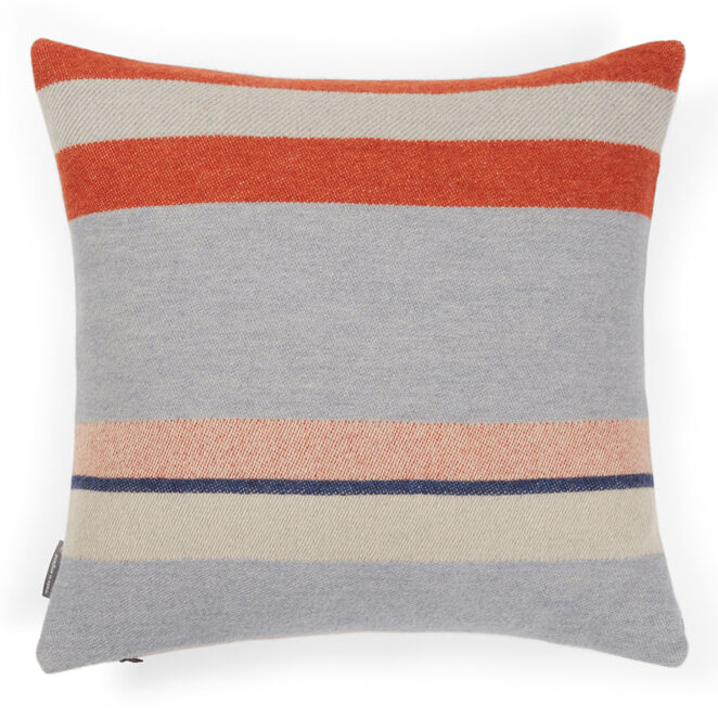 Ein künstlerisches Kissen im Bauhaus-Stil, genannt 'Stölzl Kissen', zeigt abwechselnde horizontale Streifen in Grautönen, Orange, Blau und Beige. Das Design ist minimalistisch und modern gehalten, perfekt für stilbewusste Einrichtungen.