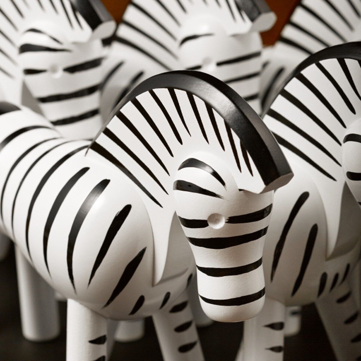 Eine Sammlung von handgefertigten Zebra-Figuren aus Holz von Kay Bojesen, dargestellt in einem dekorativen und kunstvollen Design mit schwarzen Streifen auf weißer Basis.