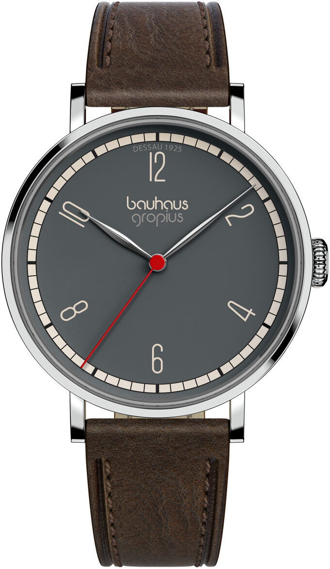 Die Abbildung zeigt eine elegante Armbanduhr aus der ZEIT-Sonderedition 'Walter Gropius Armbanduhr New Bauhaus Dessau 1925'. Die Bauhaus-inspirierte Uhr besitzt ein dunkelgraues Zifferblatt mit minimalistischen, weißen Ziffern und feinen silbernen Zeigern. Ein betonter Sekundenzeiger in Rot sowie ein schlichtes braunes Lederarmband vervollständigen das zeitlose Design. Das Gehäuse ist aus silberfarbenem Metall gefertigt.