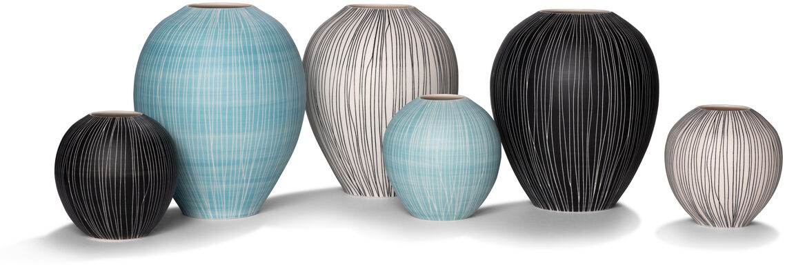 Ein Set von sechs Sgraffito-Vasen in verschiedenen Größen. Die Vasen sind in Schwarz, Weiß, Hellblau und Grau gehalten und haben ein minimalistisches, gestreiftes Design.