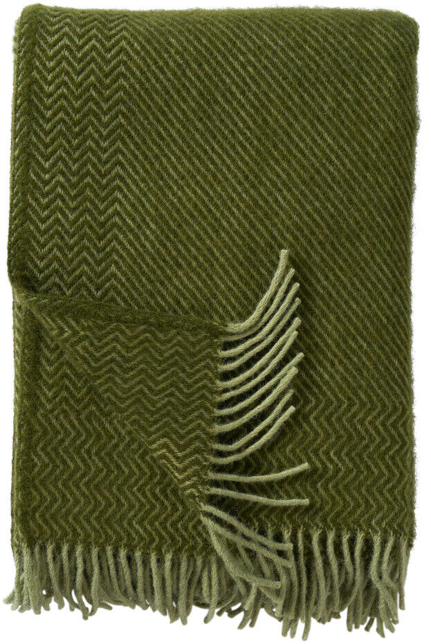Bild einer olivgrünen Decke namens »Bazaar« mit Fransendetails, die ordentlich zusammengefaltet ist.