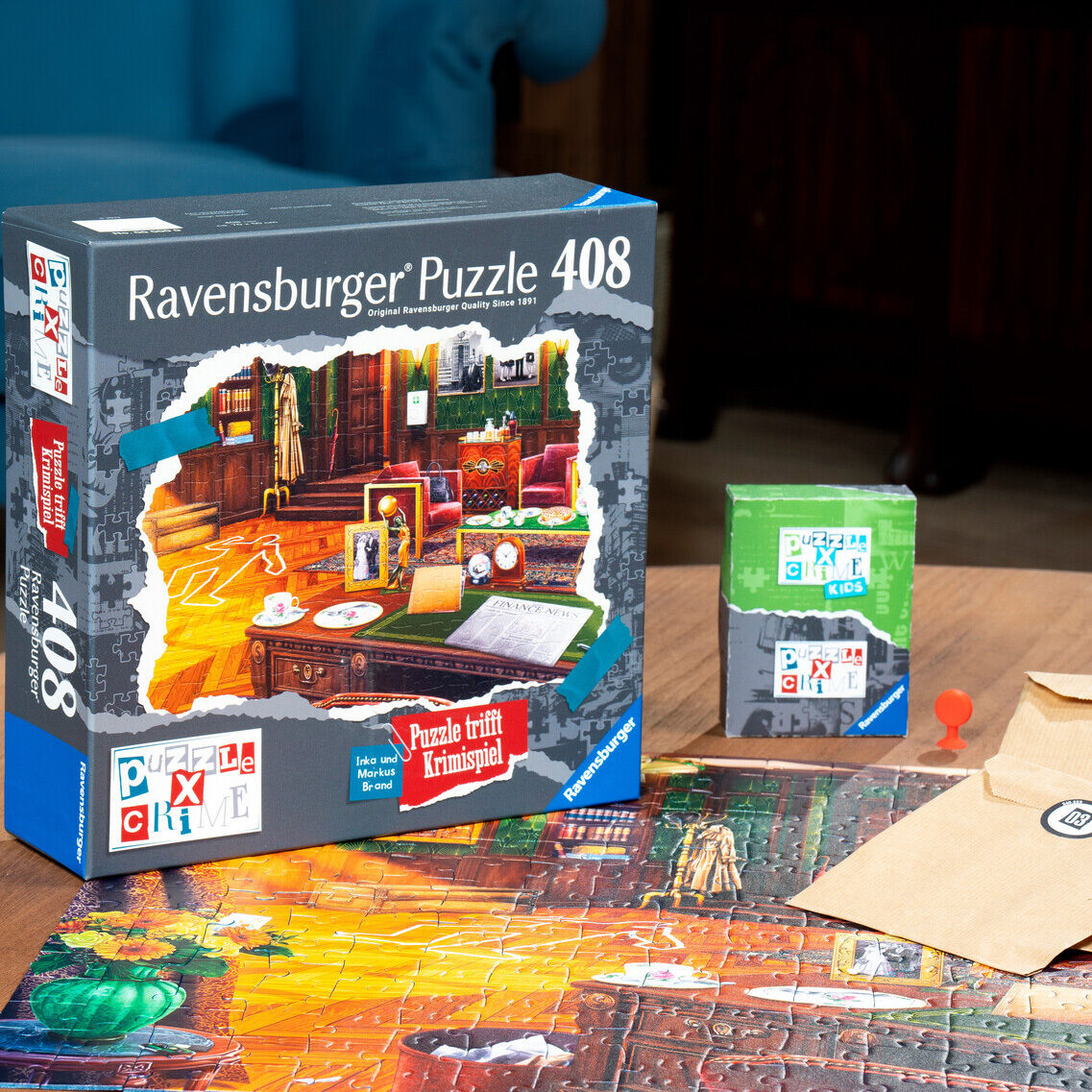 Die Verpackung des Ravensburger Puzzles »Puzzle X Crime – Ein mörderischer Geburtstag« ist zu sehen. Das 408-Teile-Krimipuzzle mit farbenfrohem Motiv zeigt eine kriminalistische Szene. Auf dem Tisch liegen Karten, neben dem Puzzle Umschläge und weitere Spielmaterialien.