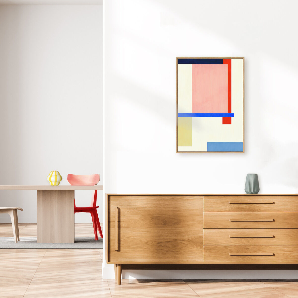 Abstraktes Leinwandbild mit geometrischen Formen und Farbfeldern in Beige, Pink, Blau und Rot hängt an einer weißen Wand über einer Holzkommode in einem modernen Wohnzimmer mit minimalistischem Einrichtungsstil.