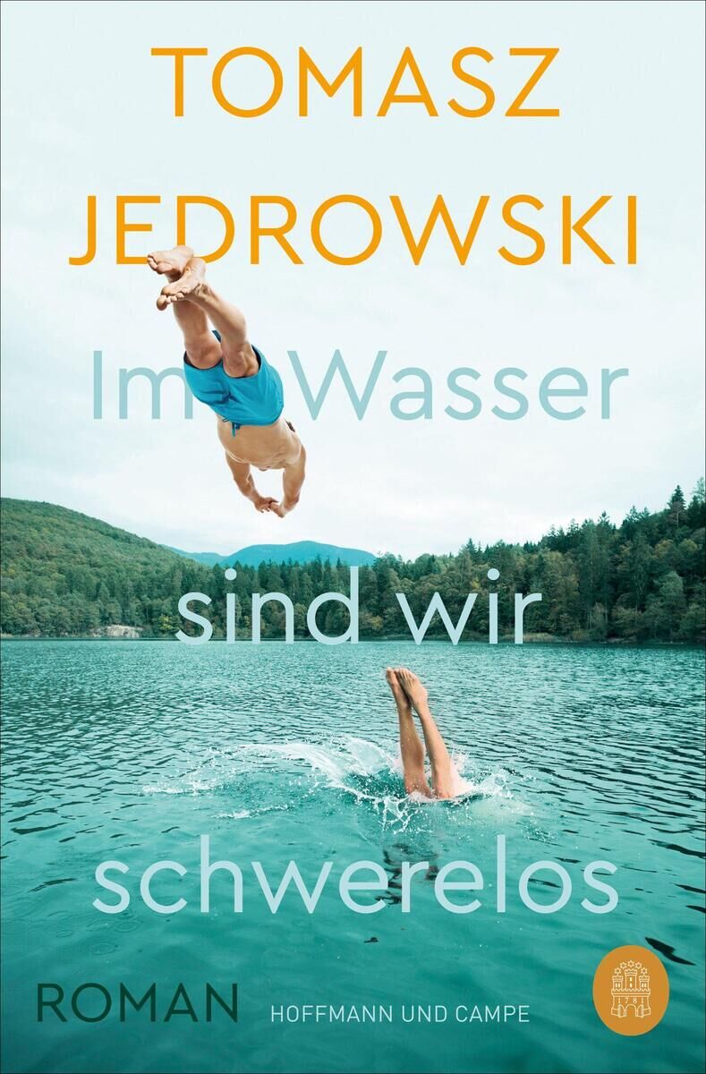 Buchcover von 'Im Wasser sind wir schwerelos' von Tomasz Jedrowski, das einen Menschen zeigt, der kopfüber in einen See springt, während ein anderer Mensch bereits im Wasser ist. Im Hintergrund ist eine bewaldete Landschaft zu sehen. Der Titel ist in türkis und weißer Schrift geschrieben, der Autorenname in gelber Schrift.
