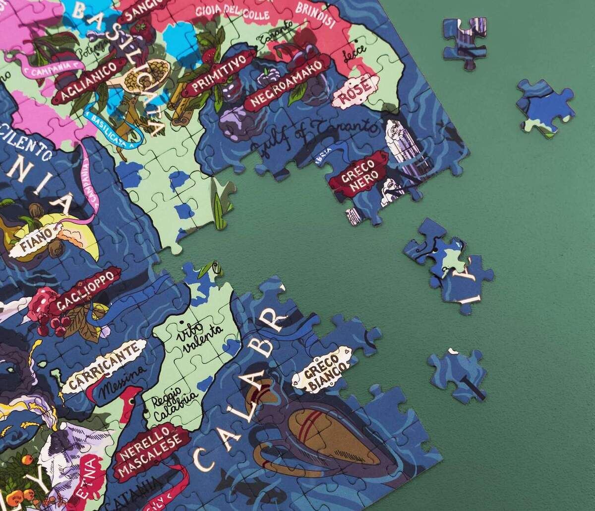 Nahaufnahme des Weinpuzzles »Italien«. Das Puzzle zeigt eine farbenfrohe Karte Italiens mit verschiedenen Weinanbaugebieten und einige lose Puzzleteile an der Seite.