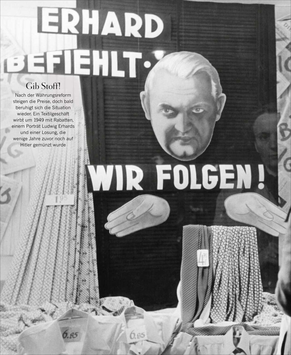Schwarz-weiß Fotografie eines Schaufensters mit einem großen Plakat von Ludwig Erhard und der Aufschrift 'ERHARD BEFEHLT: WIR FOLGEN!'. Im Schaufenster sind Stoffballen und Preisschilder zu sehen.