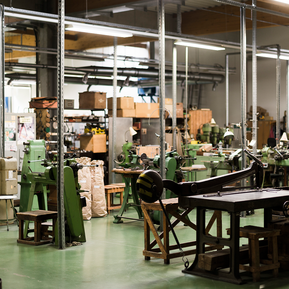 Werkstatt mit mehreren grünen Metallbearbeitungsmaschinen und Werkbänken in einer großen Halle