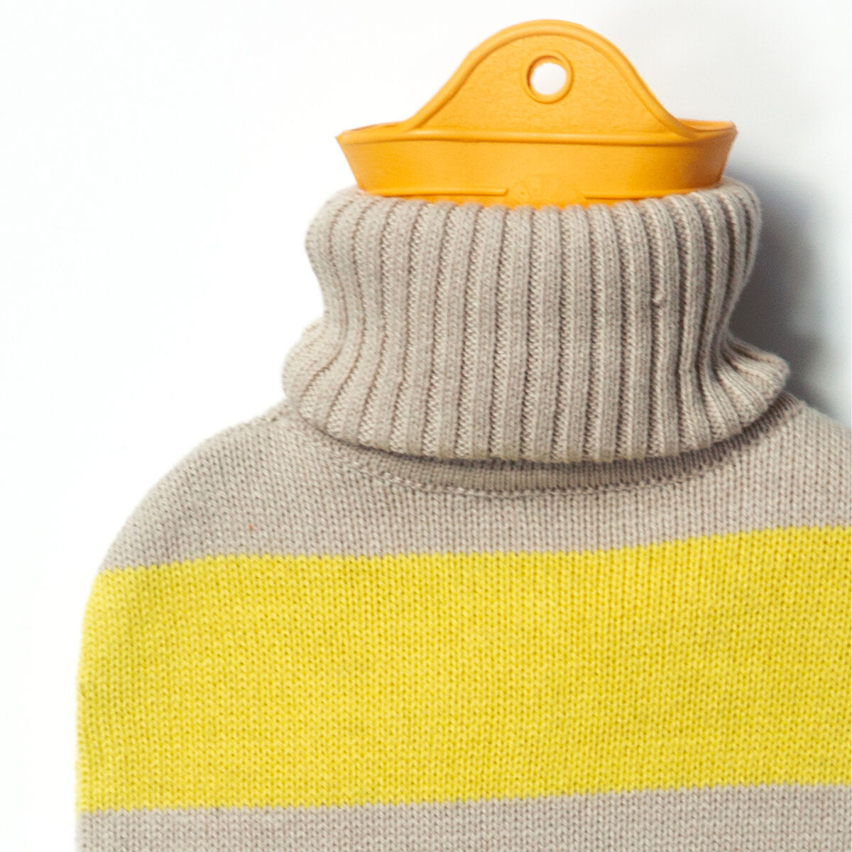 Abgebildet ist die SUITE702 Wärmflasche gestreift Gelb mit gestricktem Bezug aus beigem Stoff und markantem gelben Streifen. Der Flaschenhals aus orangefarbenem Kunststoff schaut oben hervor. Die Oberfläche erscheint weich und kuschelig, ideal für gemütliche Stunden.