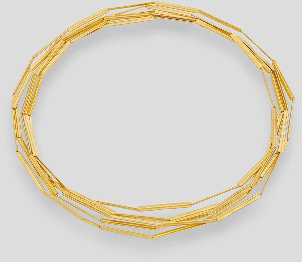 Goldplattierte Kette mit Streifen-Design auf grauem Hintergrund.