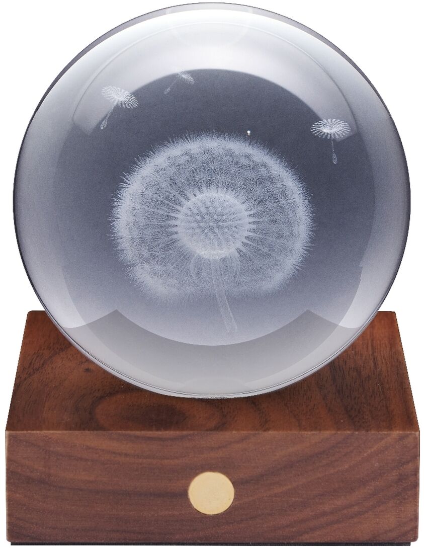 Auf einem rechteckigen Sockel aus edlem, dunklem Walnussholz mit goldenem Touchknopf steht eine klare Kristallglaskugel. Im Inneren der Kugel ist filigran eine detailreiche Pusteblume dreidimensional eingelasert. Das Design wirkt modern, elegant und hochwertig.