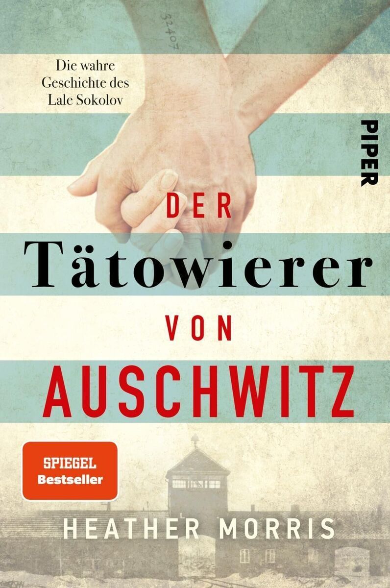 Cover des Buches 'Der Tätowierer von Auschwitz' von Heather Morris. Zwei Personen halten sich an den Händen. Im Hintergrund sind verblasste Streifen und das Bild von Auschwitz zu sehen. Der Titel ist in roten und schwarzen Buchstaben geschrieben.