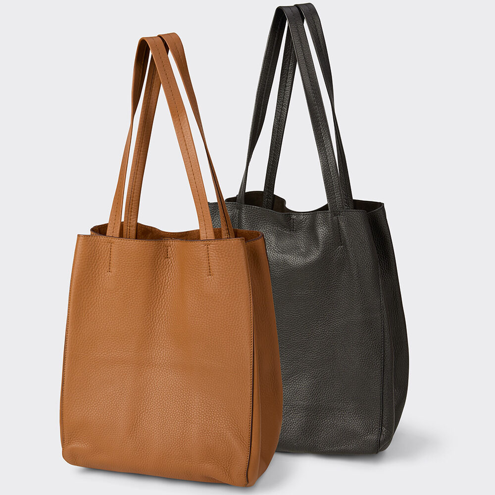 Zwei hochwertige Ledertaschen von Guerer & Guerer, Modell ZEIT-Tasche »Cep« in Cognac und Schwarz. Beide haben ein schlichtes, modernes Design mit langen Henkeln und strukturierter Lederoberfläche. Die Taschen stehen aufrecht und wirken edel und geräumig.