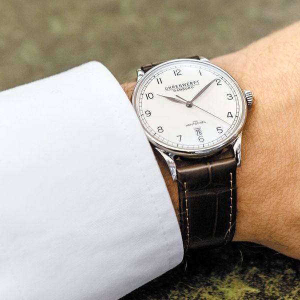 Eine klassische Herrenuhr der Uhrenedition »ZEIT 1« aus Edelstahl, die ein braunes Lederarmband und ein weißes Zifferblatt zeigt.