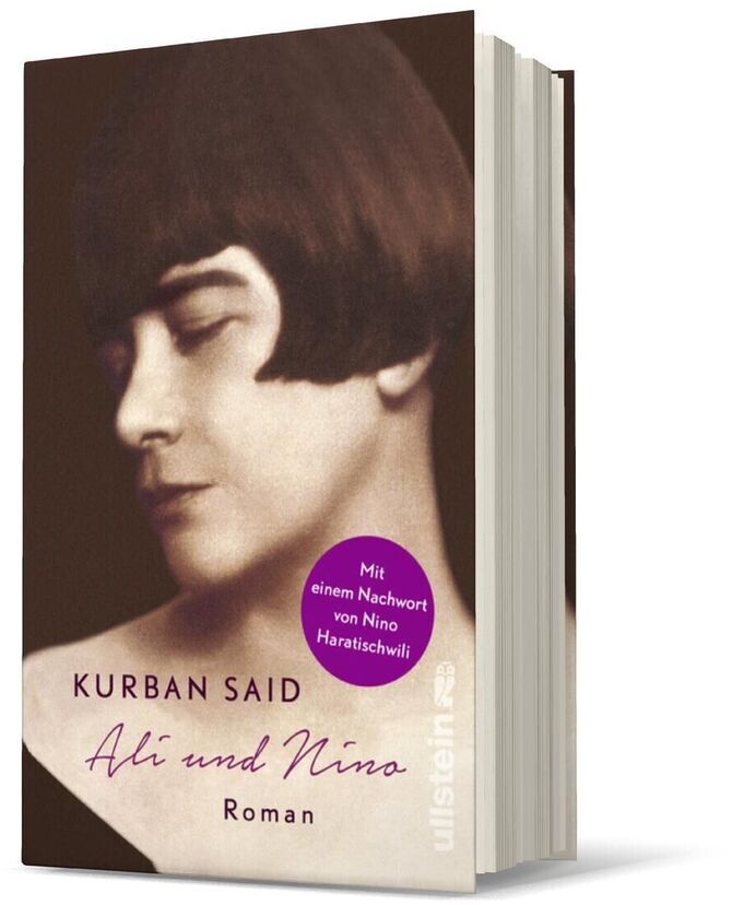 Ein Buch namens 'Ali und Nino' von Kurban Said. Der Roman hat ein Cover mit dem schwarz-weiß Porträt einer Person, inklusive einem lila Aufkleber.