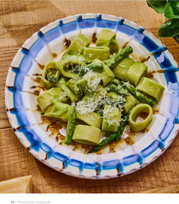 Ein Foto des Kochbuchs »Wochenmarkt - Vegetarisch«. Das Bild zeigt eine Pastagericht, dekoriert mit grünen Spargelstücken und Parmesankäse auf einem blau-weiß gemusterten Teller.