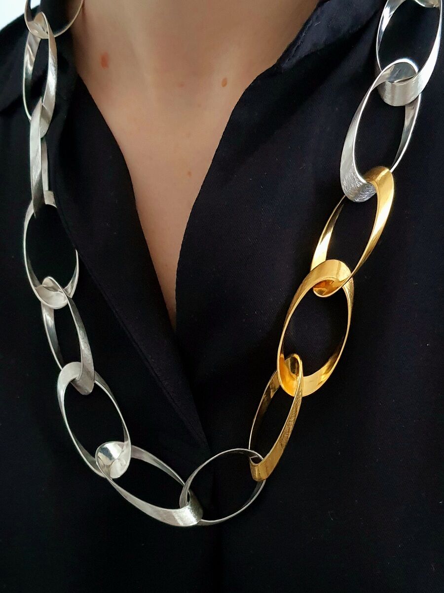 Eine elegante Halskette aus Silber und Gold, getragen von einer Person mit einem schwarzen Oberteil.