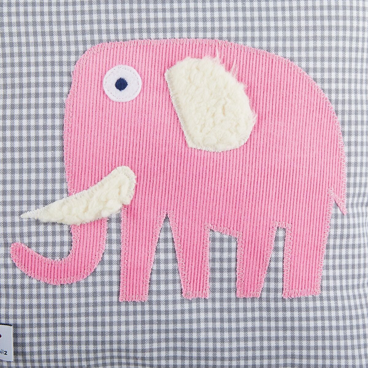 Ein Kissen mit einer Applikation eines Elefanten in Rosa auf einem grauen karrierten Hintergrund. Der Elefant hat einen weißen Stoßzahn und Ohr. Geeignet als personalisiertes Geschenk für Kinder.