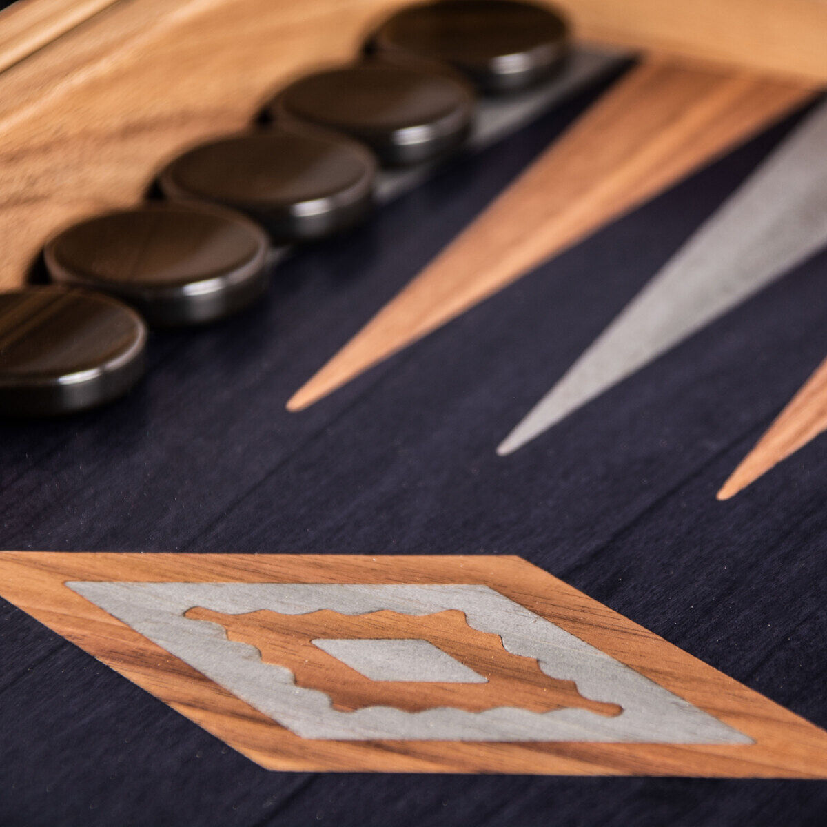 Nahaufnahme eines hochwertigen Backgammon-Spiels mit einem Brett aus Schwarzeiche und Walnussintarsien sowie dunklen, runden Spielsteinen. Das Design ist elegant und zeitlos.