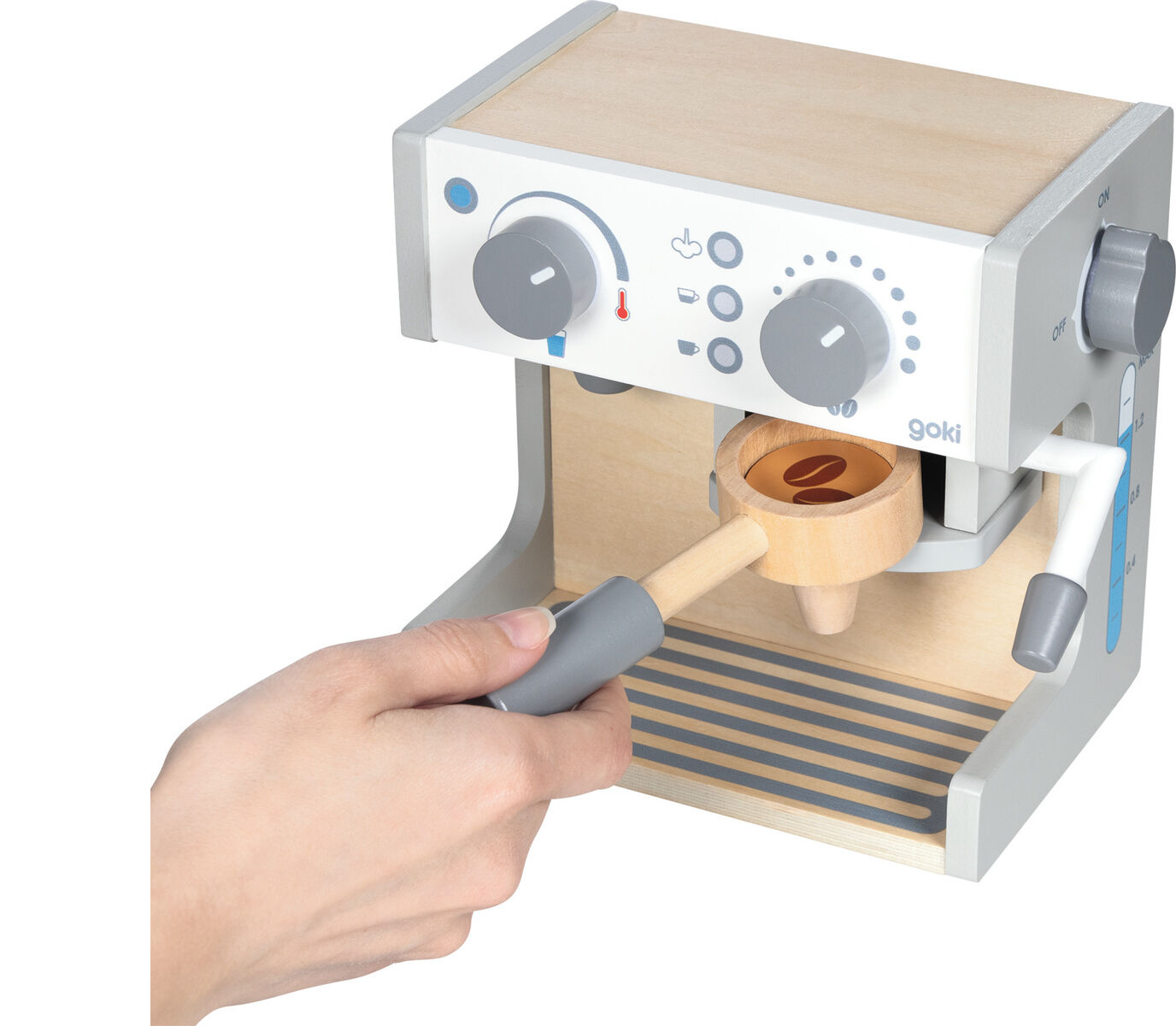 Abgebildet ist eine Espresso- und Teestation aus Holz für Kinder. Das realistisch gestaltete Spielzeug umfasst Bedienelemente, eine abnehmbare Tasse sowie einen Holzportafilter, der von einer Hand gehalten wird. Die Station ist in Naturholztönen, Blau, Grau und Weiß gehalten. Sie steht auf einer hellen Oberfläche und lädt zum Rollenspiel ein.