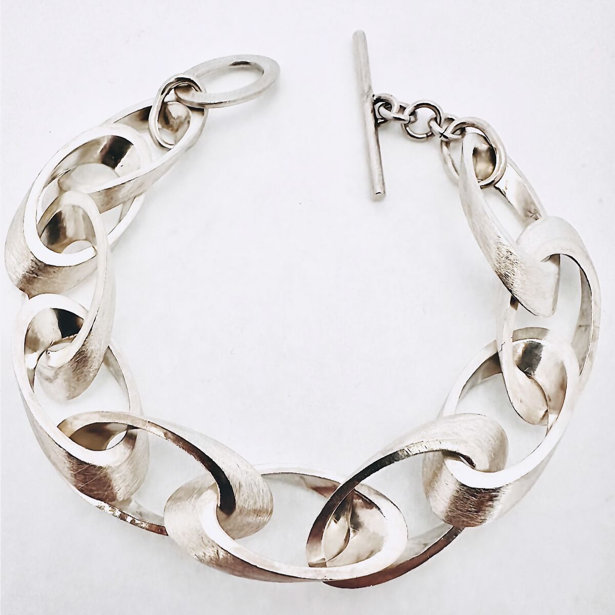 Silbernes Armband im Kettenstil mit Elipsen-Design und einem Verschluss, auf weißem Hintergrund, elegant und modern.