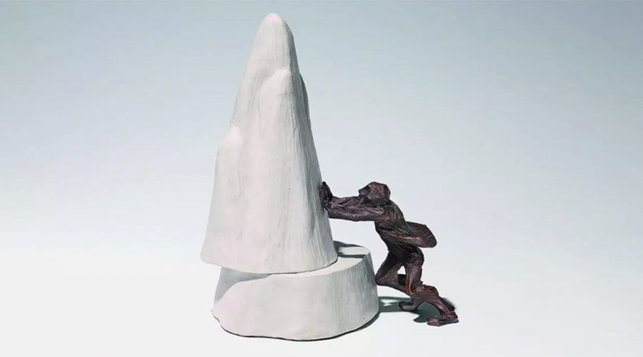 Skulptur eines Menschen, der eine große, weiße, spitze Form mit Mühe schiebt
